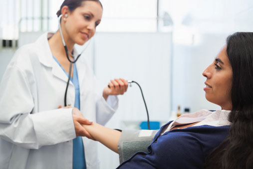 Woman gets her blood pressure checked by doctor.